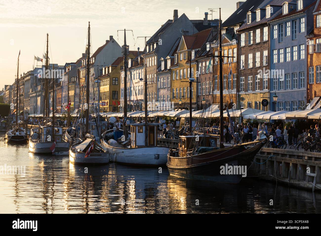 Barche e colorate case danesi tradizionali alla luce del sole serale a Nyhavn, Copenaghen, Zelanda, Danimarca, Europa Foto Stock