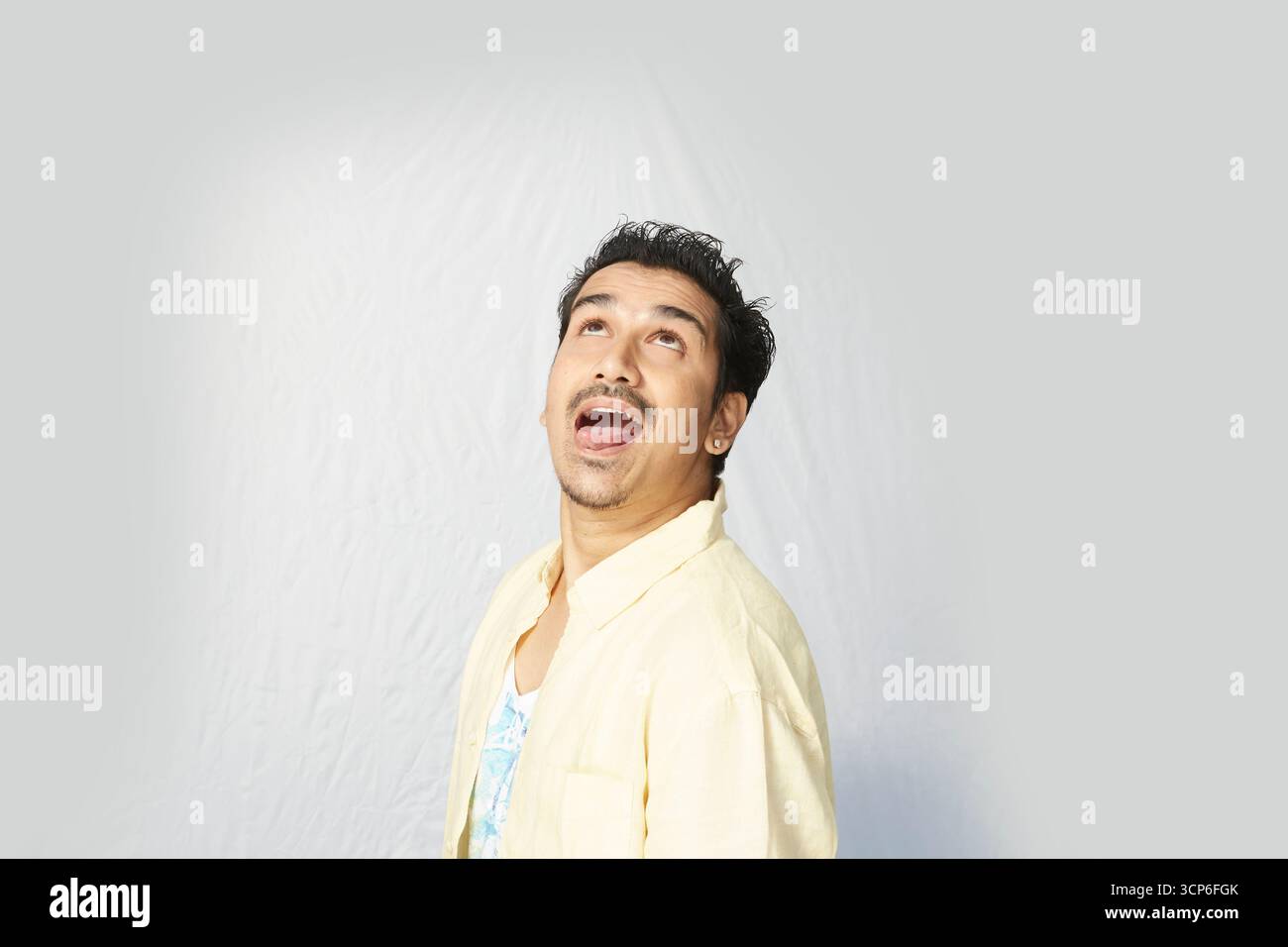 Candid Shot of a Man in a Yellow Shirt con un'espressione felice e sorpresa Foto Stock