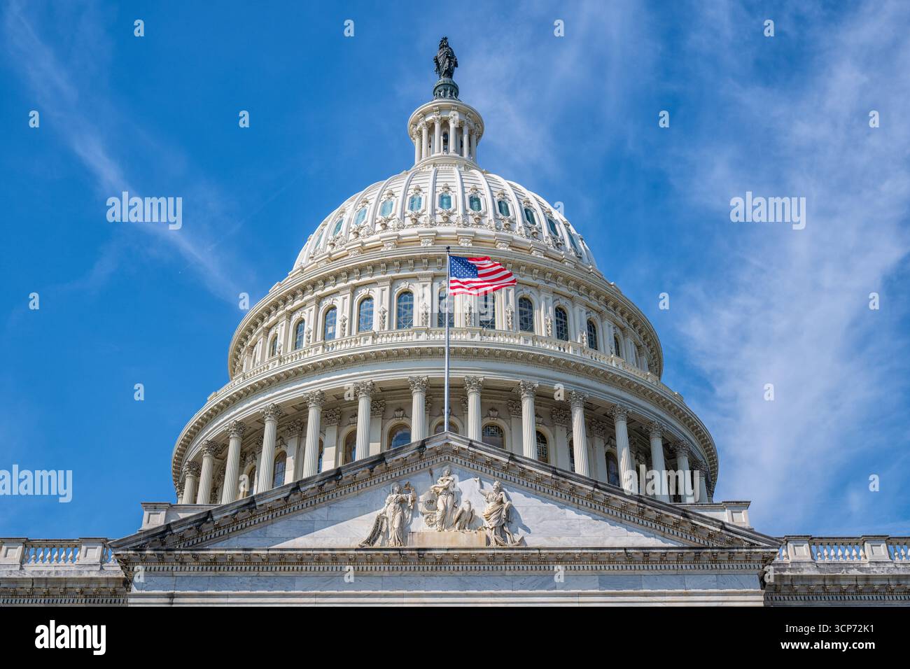 US Capitol Building Dome Washington DC // WASHINGTON DC - la cupola del Campidoglio DEGLI Stati Uniti è mostrata contro un cielo blu con nuvole mostruose. La cupola è sormontata dalla Statua della libertà e presenta elementi architettonici classici, tra cui colonne e finestre ad arco. Una bandiera americana vola da un palo sull'esterno dell'edificio. Il Campidoglio funge da luogo di incontro del Congresso degli Stati Uniti ed è un importante punto di riferimento nella capitale della nazione. La costruzione dell'attuale cupola è stata completata nel 1863 ed è un simbolo della democrazia americana. Foto Stock