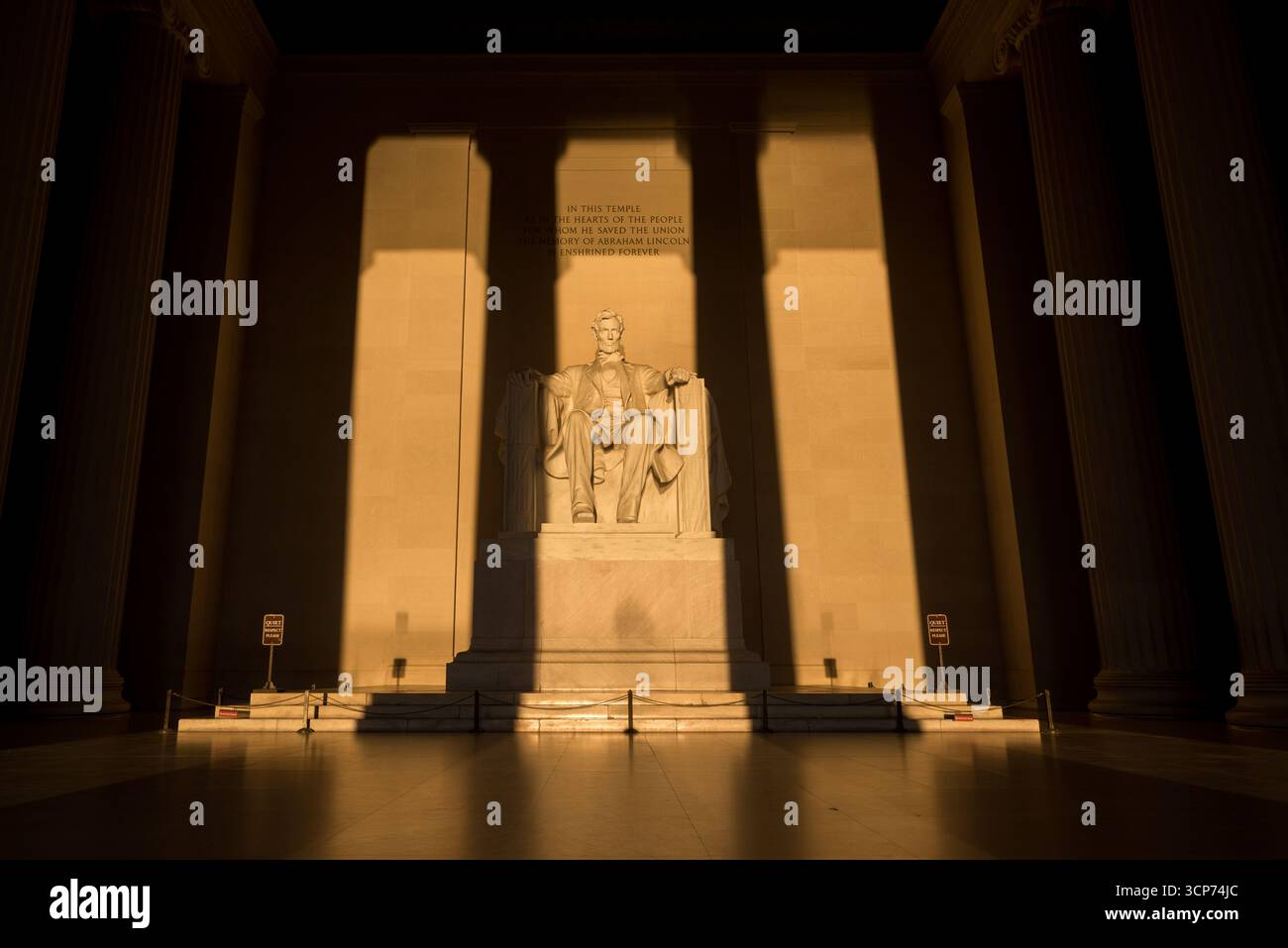 Statua del Lincoln Memorial Washington DC Vernal Equinox Sunrise // WASHINGTON DC - la statua del Lincoln Memorial è illuminata dal sole nascente sull'equinozio vernal, quando il sole sorge direttamente a est. Questo allineamento fa sì che la luce del sole fluisca direttamente nella camera principale del monumento e cada sulla figura seduta di Abraham Lincoln. Il memoriale, dedicato al 16° presidente degli Stati Uniti, è un importante punto di riferimento sul National Mall. L'iscrizione sul muro dietro la statua recita: "In questo tempio, come nei cuori del popolo per il quale ha salvato l'Unione, la memoria di Abraham Lincoln è Foto Stock