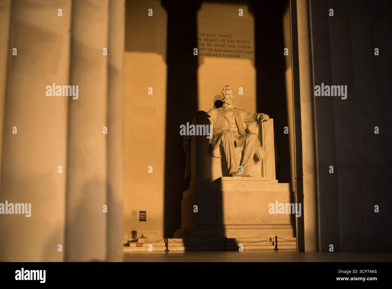 Lincoln Memorial Washington DC Vernal Equinox Sunrise // WASHINGTON DC - il Lincoln Memorial è illuminato dal sole nascente durante l'equinozio vernal, gettando lunghe ombre attraverso la camera interna. La luce del sole si allinea direttamente sulla statua seduta di Abraham Lincoln, una scultura monumentale realizzata in marmo e pietra. Questo allineamento si verifica quando il sole sorge proprio a est, un fenomeno che mette in evidenza il design architettonico del monumento. L'iscrizione all'interno del tempio recita: "In questo tempio, come nei cuori del popolo per il quale ha salvato l'Unione, la memoria di Foto Stock