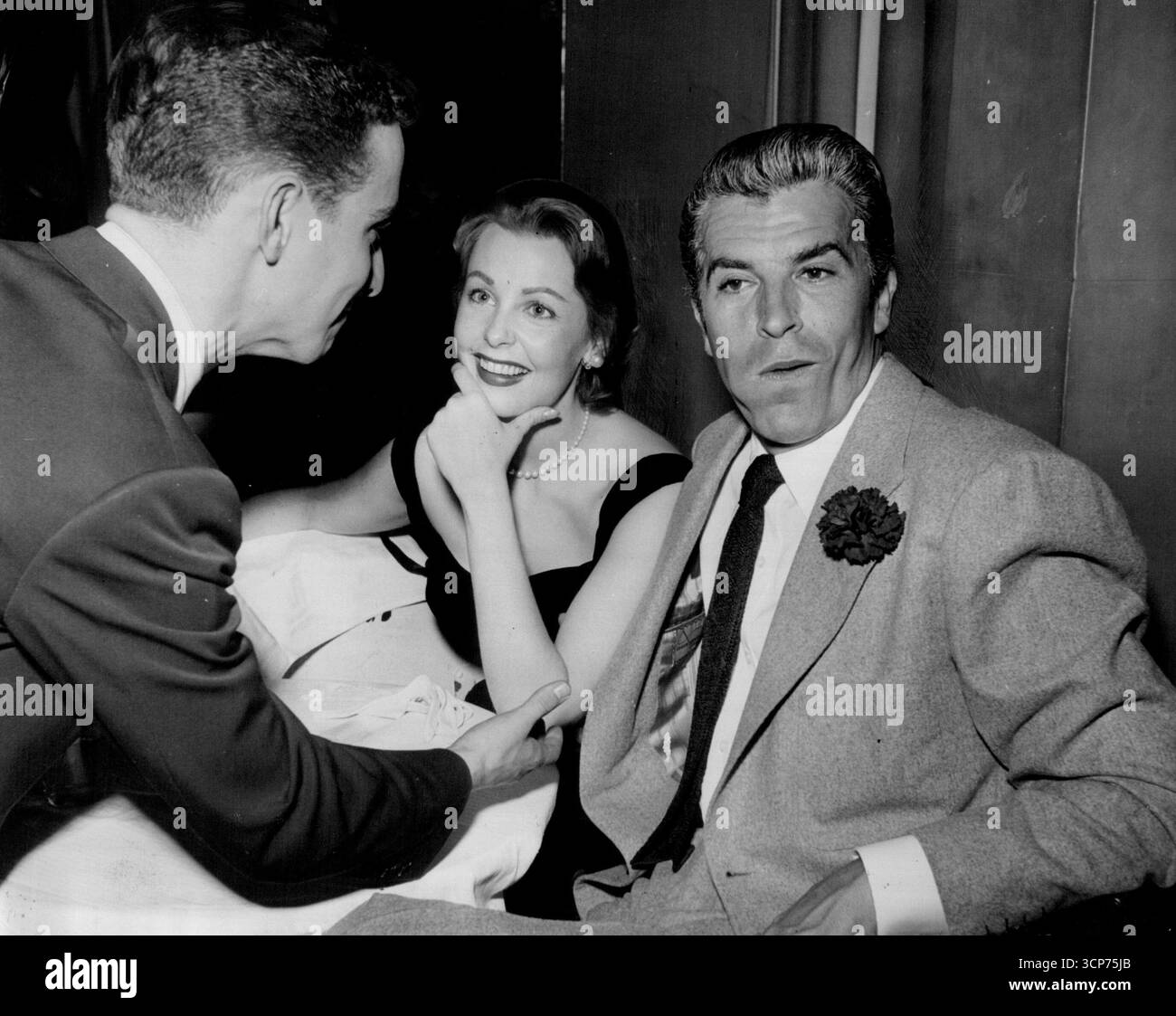 Non sappiamo cosa stesse dicendo Arlene Dahl alla sua amica, ma l'accompagnatore Fernando Lamas ha ascoltato con la lingua in guancia. 1 maggio 1953. Foto Stock