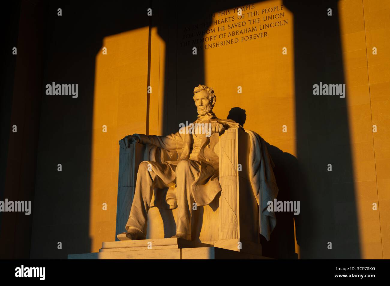 Statua del Lincoln Memorial Sunrise Washington DC // WASHINGTON DC - la statua del Lincoln Memorial è illuminata dalla luce dorata dell'alba, che getta lunghe ombre all'interno della camera principale del monumento. L'iscrizione sul muro recita: "In questo tempio, come nei cuori del popolo per il quale ha salvato l'Unione, la memoria di Abraham Lincoln è consacrata per sempre". Questo iconico memoriale, dedicato al 16° presidente degli Stati Uniti, è un punto di riferimento significativo situato sul National Mall. La statua stessa, scolpita da Daniel Chester French, raffigura Lincoln in una posa contemplativa. Il progetto del memoriale e.. Foto Stock
