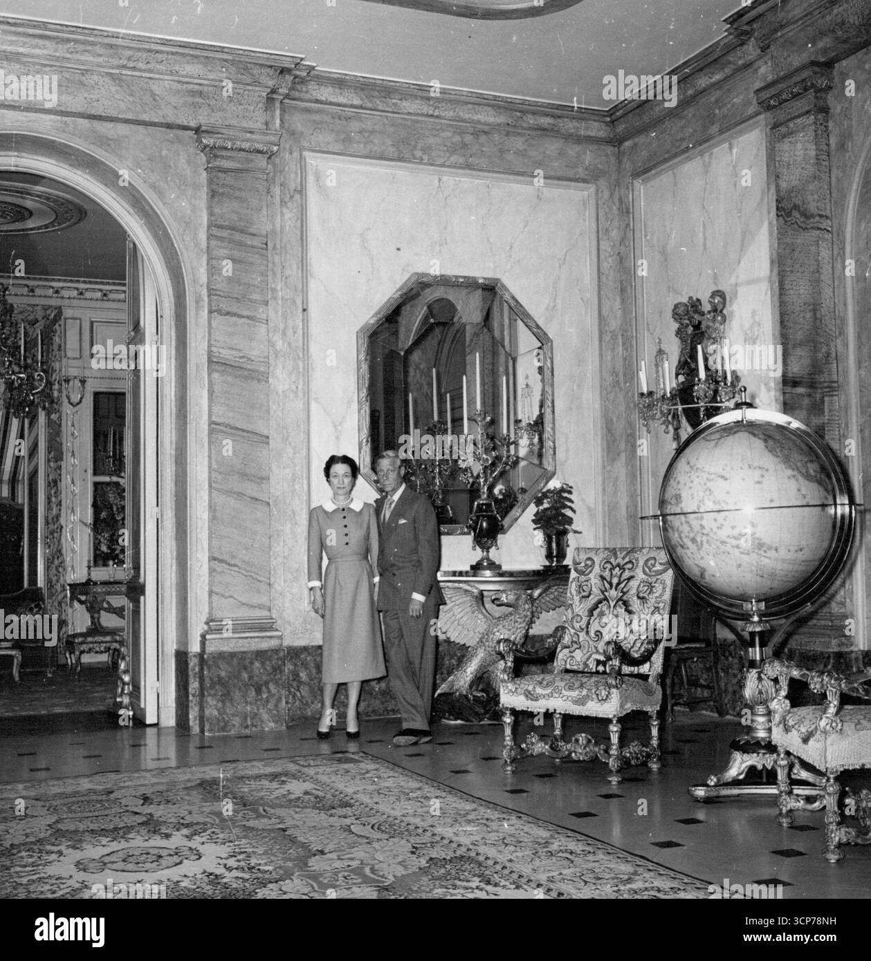 Candelabri esotici appesi in una sala d'ingresso rivestita di marmo verde e rosa e tappezzata con tappeto persiano. Due sedie Luigi XIV riccamente intagliate hanno stabilito il periodo. Luglio 26, 1955. (Foto di Daily Mirror) Foto Stock