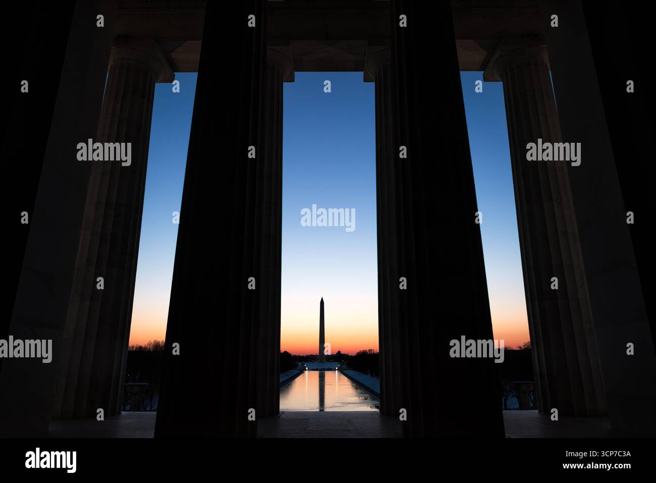Colonne del Lincoln Memorial che incorniciano il Washington Monument al tramonto Washington DC // WASHINGTON DC - il Washington Monument è incorniciato dalle colonne del Lincoln Memorial durante il tramonto. Il Lincoln Memorial, un monumento in onore del 16° presidente degli Stati Uniti Abraham Lincoln, è un importante punto di riferimento nel National Mall. Il Washington Monument, un obelisco costruito per commemorare George Washington, il primo presidente degli Stati Uniti, è visibile in lontananza. Questa vista cattura i monumenti iconici della capitale degli Stati Uniti. Foto Stock