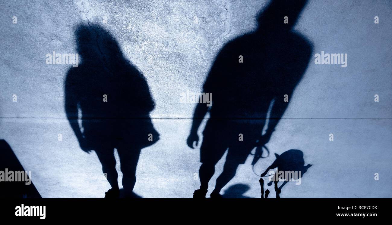 Shadow silhouette di una coppia e di un uomo cammina un cane al guinzaglio, di notte Foto Stock