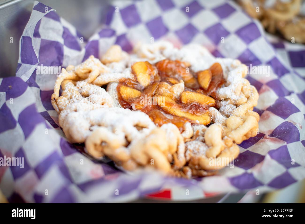 Torta a imbuto con cannella di mele e cannella Frederick Fair Frederick Maryland // FREDERICK, Maryland - Una torta a imbuto condita con cannella di mela viene servita alla Great Frederick Fair, che si tiene presso la Frederick Fairgrounds di Frederick, Maryland, Stati Uniti. La confezione fritta è spolverata con zucchero a velo e servita in carta viola e bianca a scacchi. La Great Frederick Fair è una delle più antiche fiere della contea negli Stati Uniti, risalente al 1855. Foto Stock