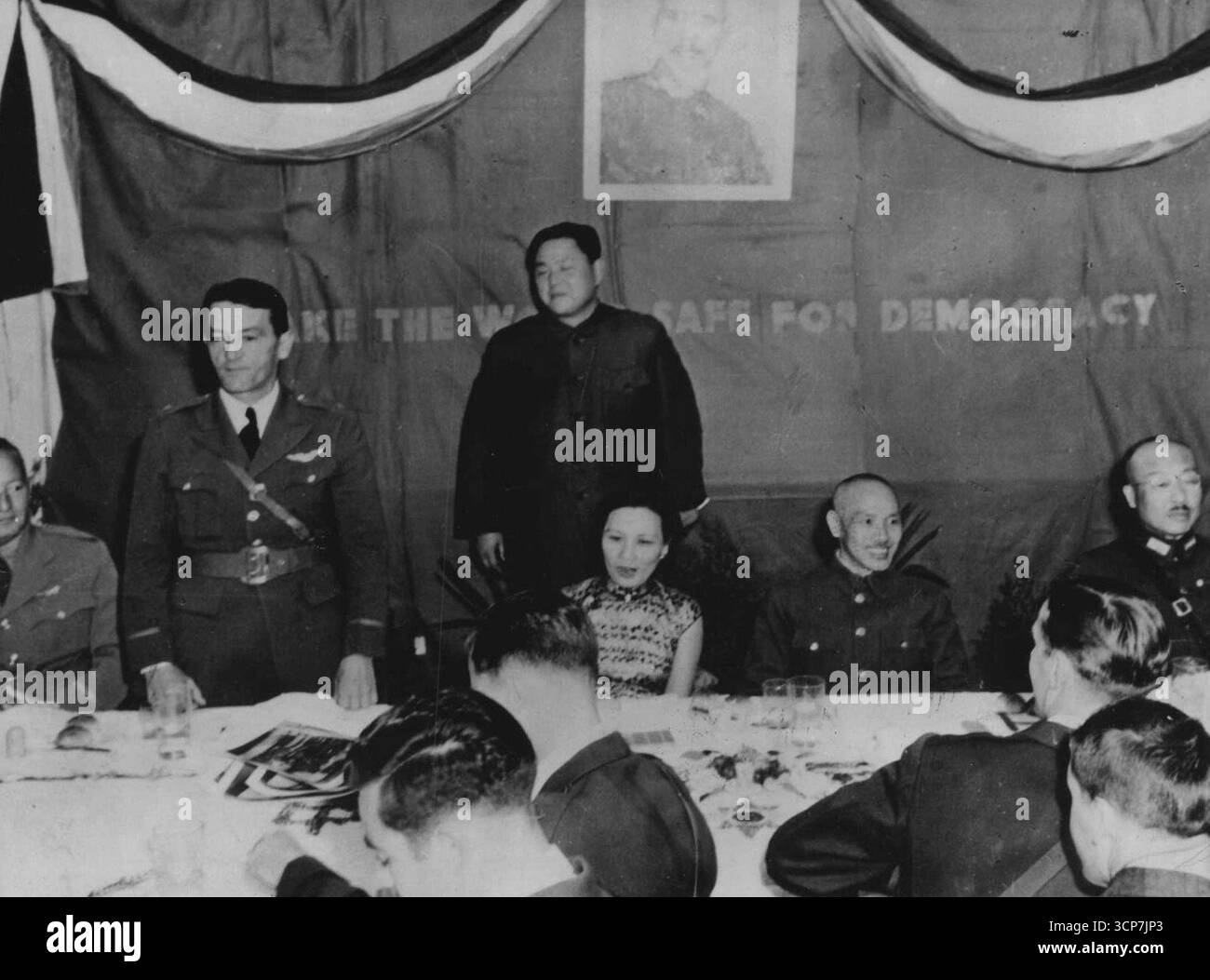 Le "Tigri volanti" del gruppo volontario americano, il cui audacia ed eroismo volando per la Cina contro i giapponesi hanno conquistato loro il rispetto del mondo, arco onorato a Kunming, in Cina, in una cena data dal Generalissimo Chiang Kai-Shek e dalla Mme. Chiang. Qui Brig. Il generale Claire L. Chennault (in piedi, a sinistra), Comandante della A. V. G., riconosce che il Tribute ha pagato i suoi volantini. Alla sua sinistra seduta, ci sono la mamma. Chiang Kai-Shek e il Generalissimo. Il generale Chennault elogiò i suoi colleghi cinesi e dichiarò che questi uomini avrebbero aiutato la difesa della Cina fino all'ultimo. 8 marzo 1943. Foto Stock