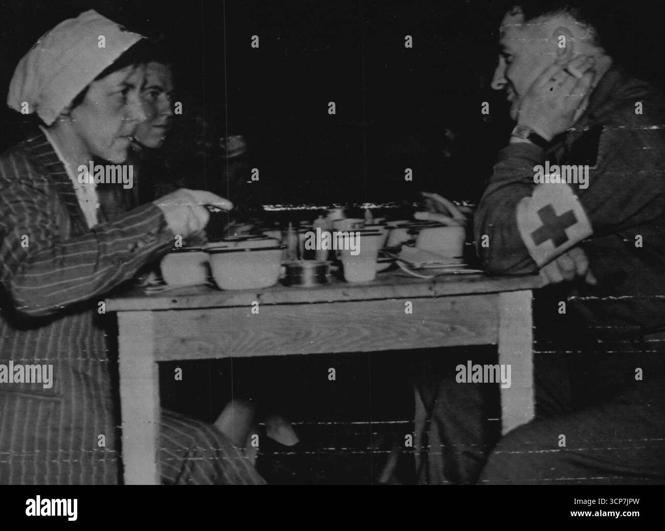 Le infermiere tedesche catturate mangiano nell'ospedale americano di Cherbourg -- infermiere tedesche, catturate durante la battaglia di Normandia mangiano con un cappellano americano nella sala pasticceria di un ospedale americano a Cherbourg. Gli infermieri furono poi restituiti alle linee tedesche sotto una temperatura. La fanteria americana liberò il porto di Chorbourh il 26 giugno 1944. Questa è una foto della radio inviata da Londra agli Stati Uniti. 24 luglio 1944. (Foto dell'Office of War Information Picture statunitense) Foto Stock