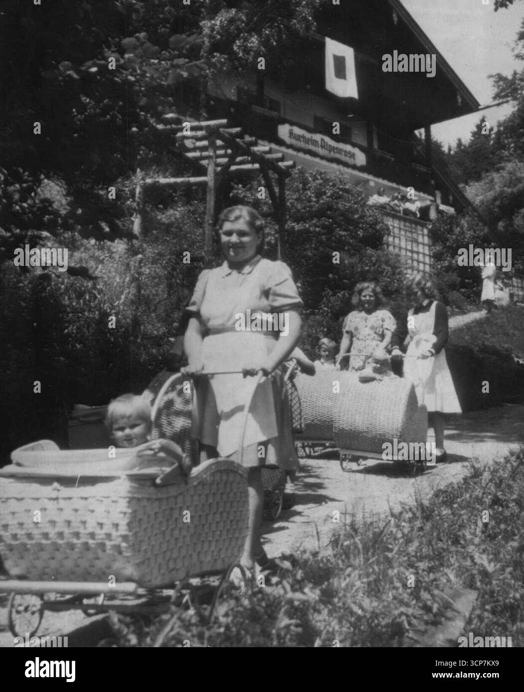 Nuova generazione: I bambini in ruota tedesco infermieri in carrozze fantasia in una casa 'sdraiato' vicino Monaco. La bandiera sull'edificio indica che questo è uno degli alberghi convertiti in maternità per le ragazze sposate e non sposate. Luglio 16, 1945. Foto Stock