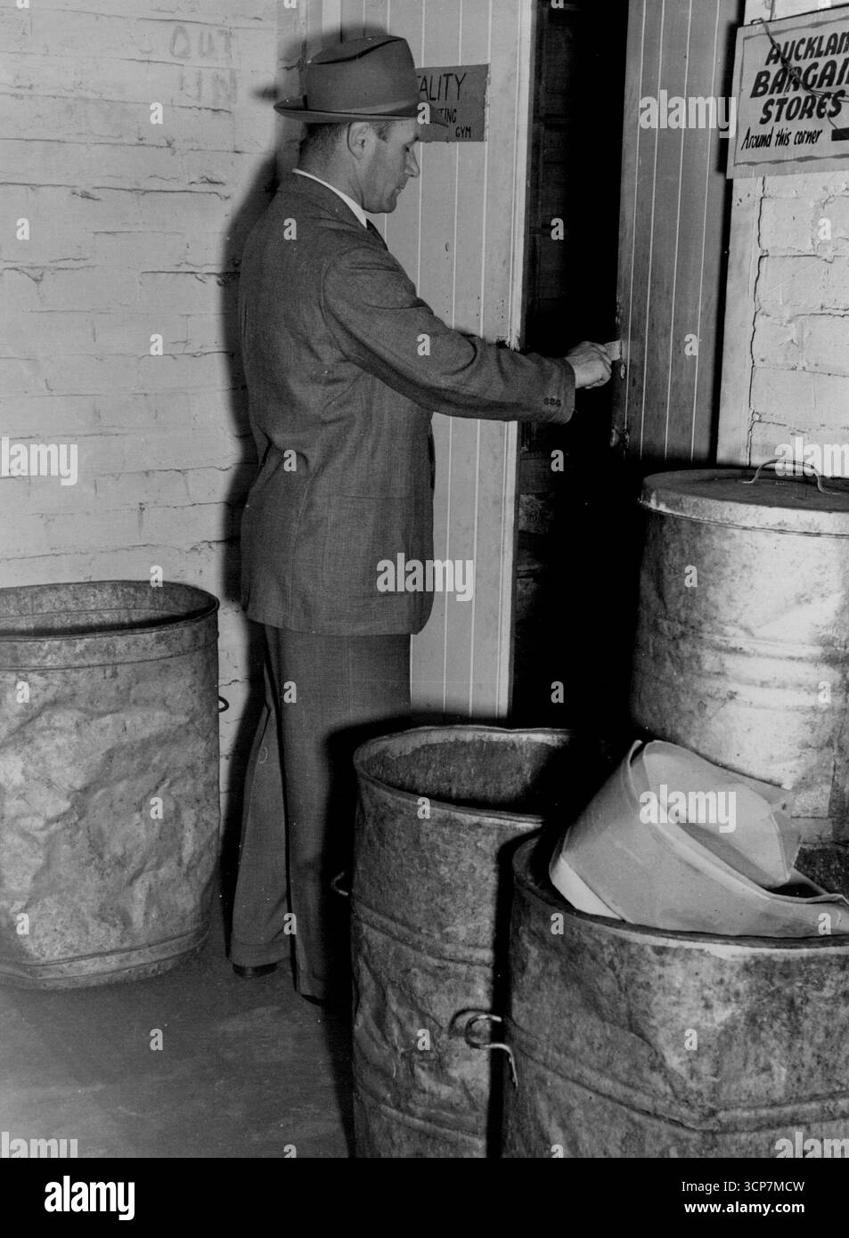 I bidoni della spazzatura Harold Cleghorn quasi bloccano la porta d'ingresso al "Dungeon". Spesso, quando metteva da parte un bidone della spazzatura, un grosso topo correva e scappava via. Ne ha uccisi più di uno con uno dei suoi otto. 17 novembre 1950. Foto Stock