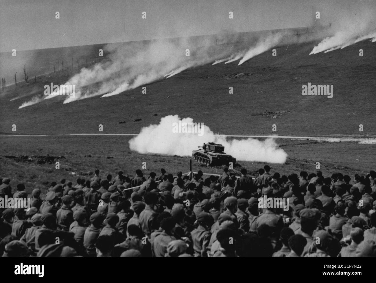 Grandstand Vista di Una "battaglia" - soldati che guardano un carro armato in azione sul "campo di battaglia" fumante. Un battaglione di fanteria, uno squadrone di un reggimento corazzato, prese parte ad una dimostrazione di "attacco su un campo minato" presso la School of Infantry, Warminster, Wiltshire. La dimostrazione era intitolata "Attack". 22 maggio 1949. (Foto di Reuterphoto). Foto Stock