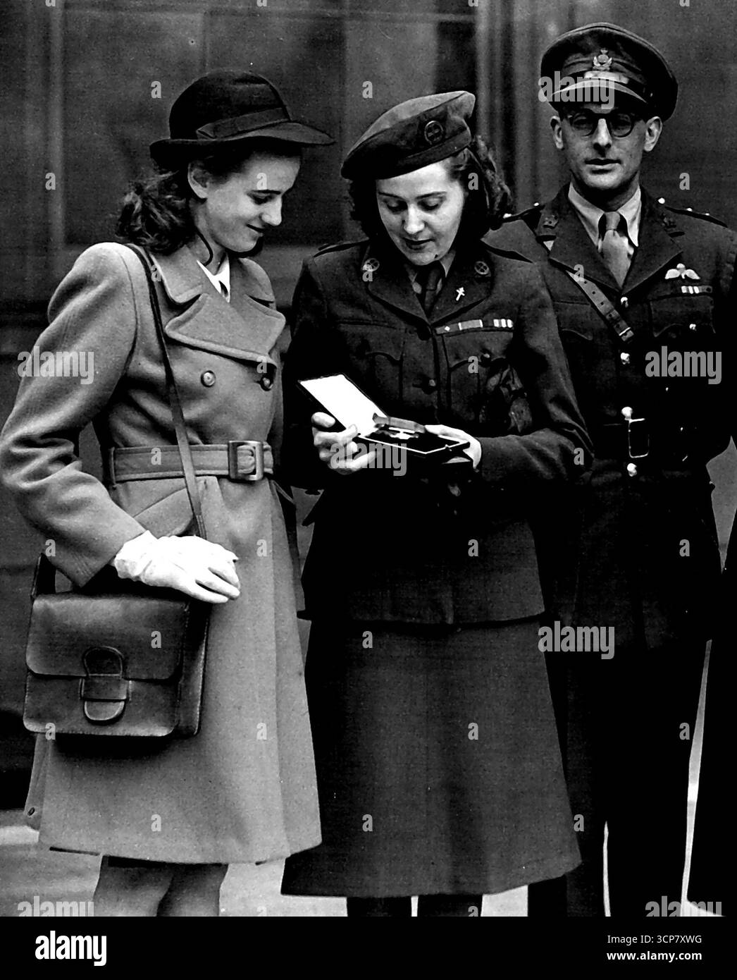 L'eroina di guerra numero uno per i servizi resi -- la signora Sansom e il capitano Peter Churchill lasciano Buckingham Palace dopo aver ricevuto decorazioni da re Giorgio per il loro lavoro come agenti segreti con la resistenza francese durante la guerra. La signora Sansom ricevette la George Cross, la prima donna a farlo, e il capitano Peter Churchill fu insignito del Distinguished Service Order. Francoise Sansom ammira la decorazione di sua madre. 1° novembre 1953. Foto Stock