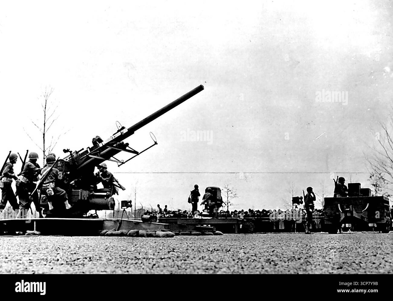 Mechanical 'Brain punta U.S. Anti-Aircraft Guns -- Un US 90-mm. l'equipaggio di cannoni antiaerei salta in azione mentre l'arma ruota verso un bersaglio durante una dimostrazione dei metodi di tiro. La pistola è un'arma mirata da un direttore di pistola elettrica mostrato sul camion. Nel giro di pochi secondi il regista nota la velocità e l'altezza di un luogo, consente la deriva, la spinta gravitazionale e la densità dell'aria, punta la pistola e imposta la miccia in modo che un guscio esploda a distanza letale dal bersaglio. Il maggior generale Levis H. Campbell Jr., capo dell'U.S. Army Ordnance, descrive il direttore come "uno dei più grandi progressi nel campo Foto Stock