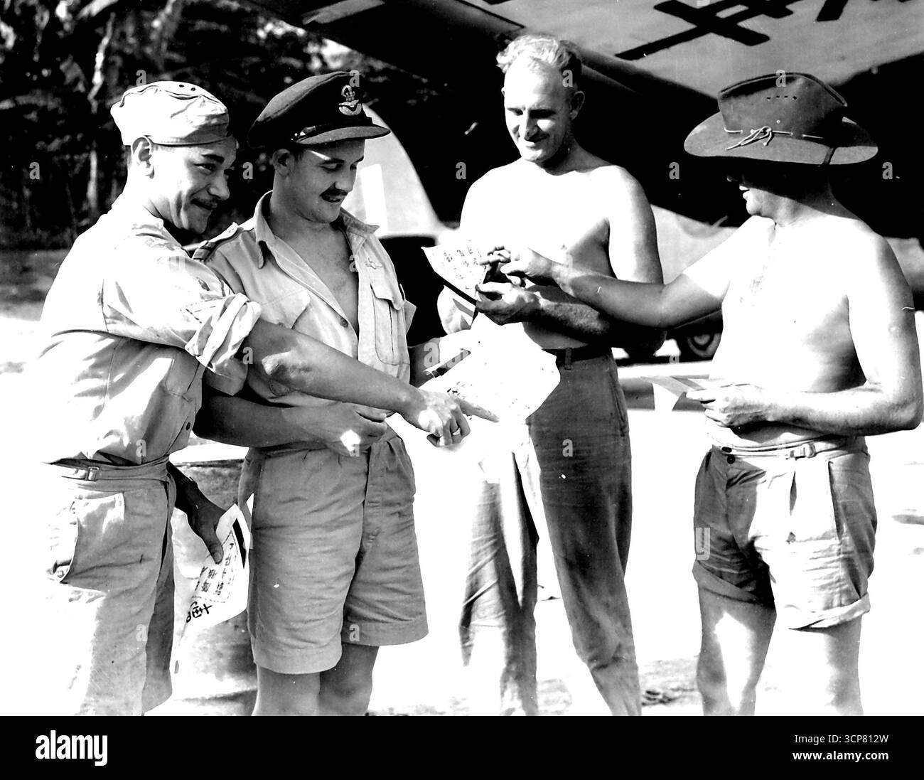 Membri della RNZAF e della RAAF nell'area HQ 2 Corps, che guardano i volantini di resa prima di distribuirli. Il Beaufort, che consegnerà ai giapponesi gli opuscoli di resa, ha il lato inferiore delle sue ali dipinto "il Giappone si arrese". Il personale identificato è:- F-Sgt T.E. Wipiti (1), P-o R.B. Lamb (2), LAC R.P. Hughes (3), LAC F. Johansson (4). 15 agosto 1945. (Foto dell'Australian War Memorial). Foto Stock