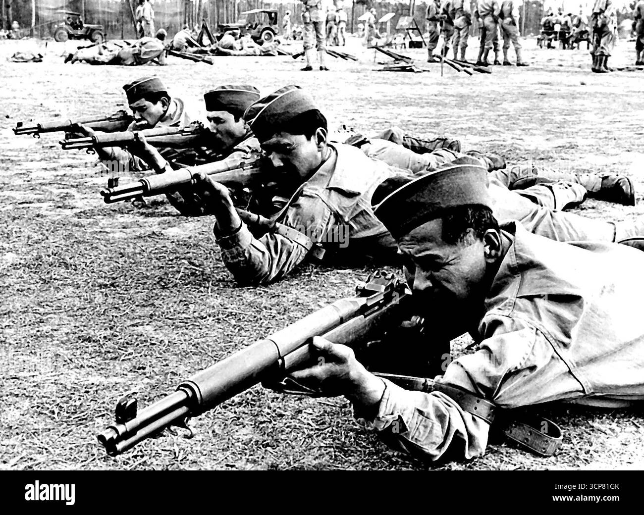 Fanti dell'esercito americano di discesa messicana -- questi tiratori dell'esercito degli Stati Uniti, in addestramento presso un sud degli Stati Uniti ***** Sono tutte di origine messicana. Nati in Messico da genitori messicani, sono cittadini statunitensi del paese di confine tra Stati Uniti e Messico. Molti parlano solo la lingua dei loro padri, quindi l'esercito emette comandi sia in spagnolo che in inglese. Stando inclini a terra in questa foto, stanno imparando a maneggiare il fucile Garand a fuoco rapido. 12 febbraio 1943. (Foto dell'Office of War Information Picture statunitense). Foto Stock