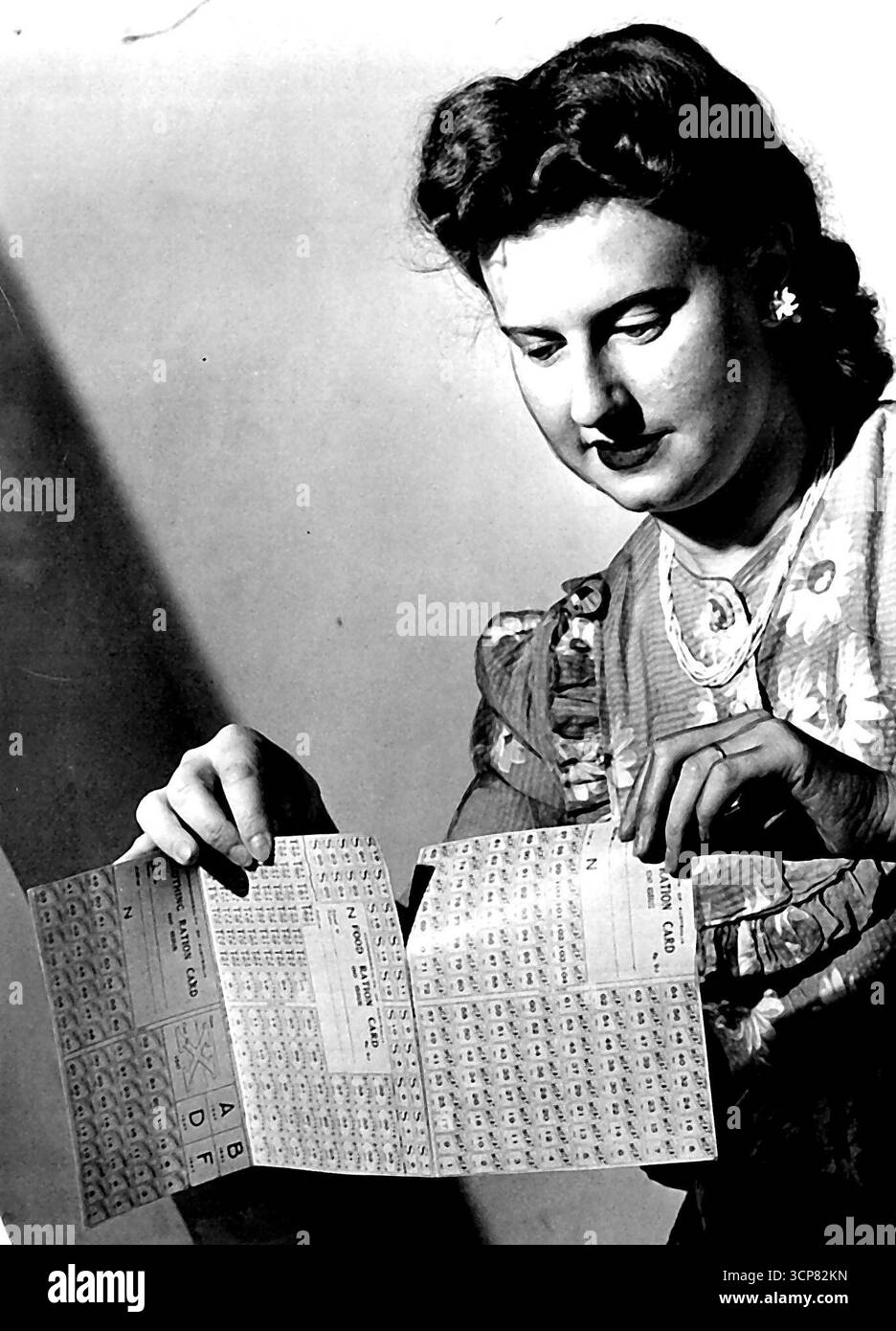 I suoi nuovi buoni le verranno consegnati il 7 dicembre, in una cartella delle carte, mostrata qui dalla signora Joan Sutton, della Commissione di razionamento. Si tratta di tre fogli staccabili - per la carne (104 coupon), per gli alimenti (26 zuccheri, 39 burro e 52 buoni tè) e per l'abbigliamento (56 coupon). 25 novembre 1946. Foto Stock