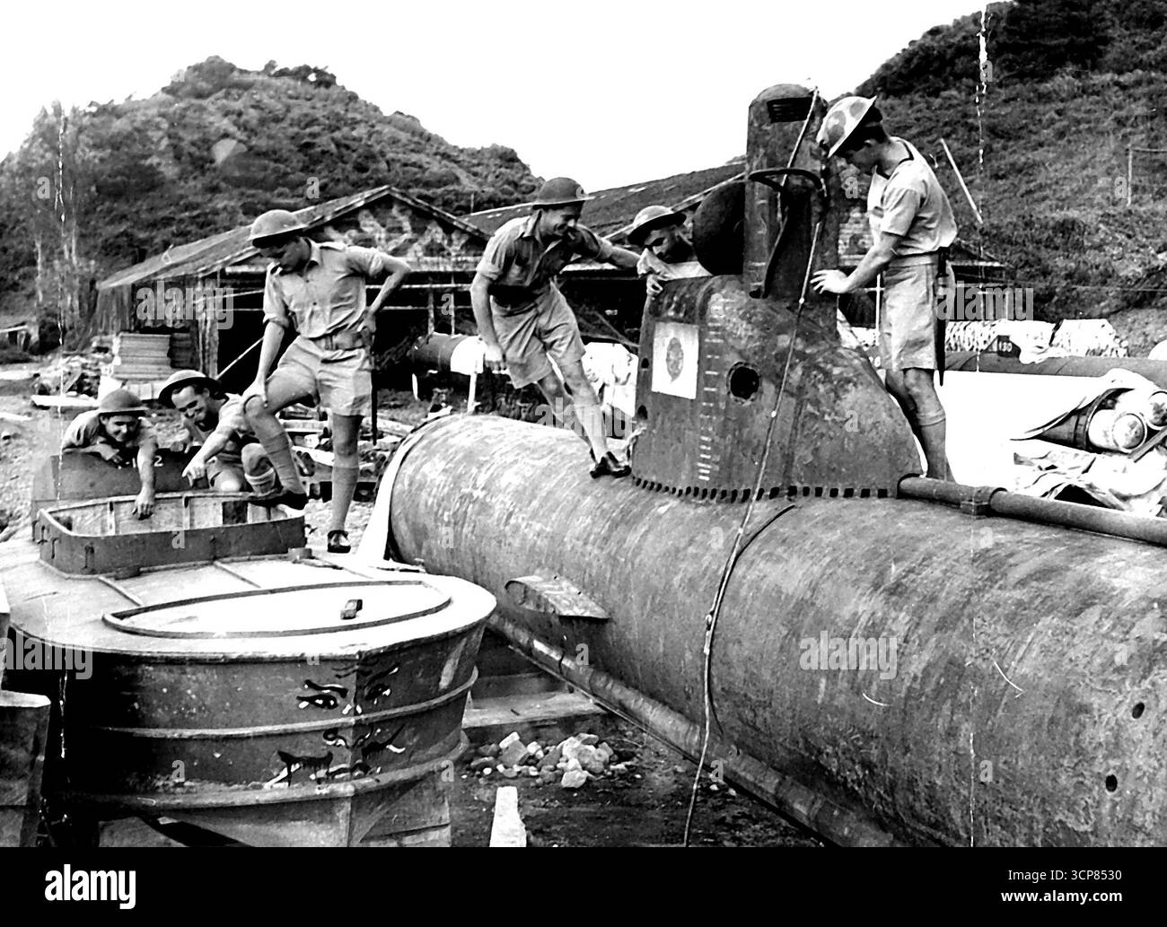 I rating navali australiani di H.M.A.S. Napier trovano molto interesse per un lancio suicida giapponese e un sottomarino nano insieme nella base navale di Yokosuka. Sono (al lancio) Able Seaman Kevin Sorrenson di Coorparoo Queensland, Able Seaman Les Coad di Ballarat Victoria, Able Seaman Ian Cox di South Yarra Victoria, e (sul sommergibile) il sottufficiale Alan Mole di Mitcham South Australia, Able Seaman Myer White di Prahran Victoria e Able Seaman Max Dillon di Cygnet Tasmania. 1° gennaio 1945. (Foto di Australian Official Photo). Foto Stock