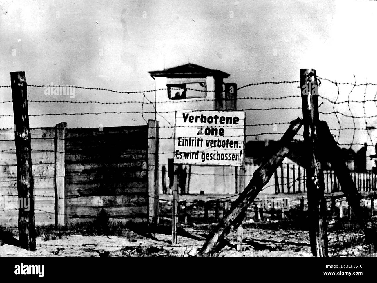 Prime immagini esclusive del campo di concentramento sovietico. I russi rianimano il famigerato Sachsenhausen -- campo di Sachsenhausen sorvegliato da guardia e filo spinato. Il cartello recita: Zona vietata. Immissione vietata. Vi spareranno. Mitraglieri e uomini di fucili abbattono queste torri. Queste prime foto del campo di Sachsenhausen governato dai sovietici sono state scattate, a rischio della sua vita, da un fotografo - deliberatamente non identificato - accovacciato tra lapidi a duecento metri da tiratori e mitragliatori russi. Secondo i rapporti ci sono circa 14.500 uomini e 1.500 donne internati a Sachse Foto Stock