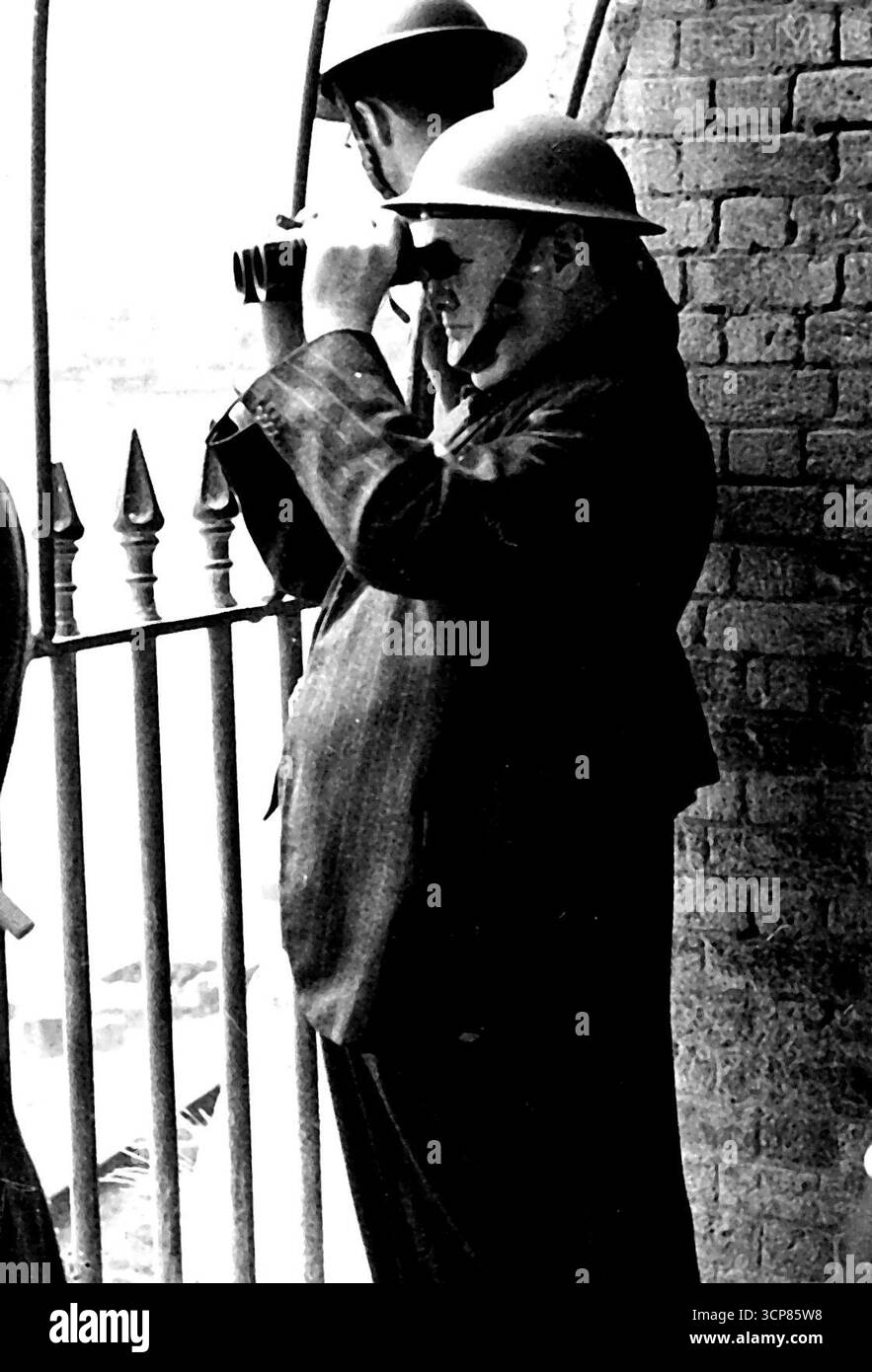 Premier Watches Air Battle con elmetto in acciaio -- il signor Winston Churchill nel posto di osservazione da cui ha assistito a una battaglia aerea. Il sindaco di dover è sulla sinistra. Signor Winston Churchill, il Premier indossava un casco d'acciaio mentre guardava le battaglie aeree durante la sua visita a dover. Il Premier ispezionò anche i danni provocati dai raid aerei a dover e Ramsgate nonostante il fatto che ci fosse un avvertimento quasi continuo durante la sua visita. Il Premier ha visto una battaglia aerea in cui due macchine sono state abbattute. 30 agosto 1940. (Foto di British Official Photograph). Foto Stock
