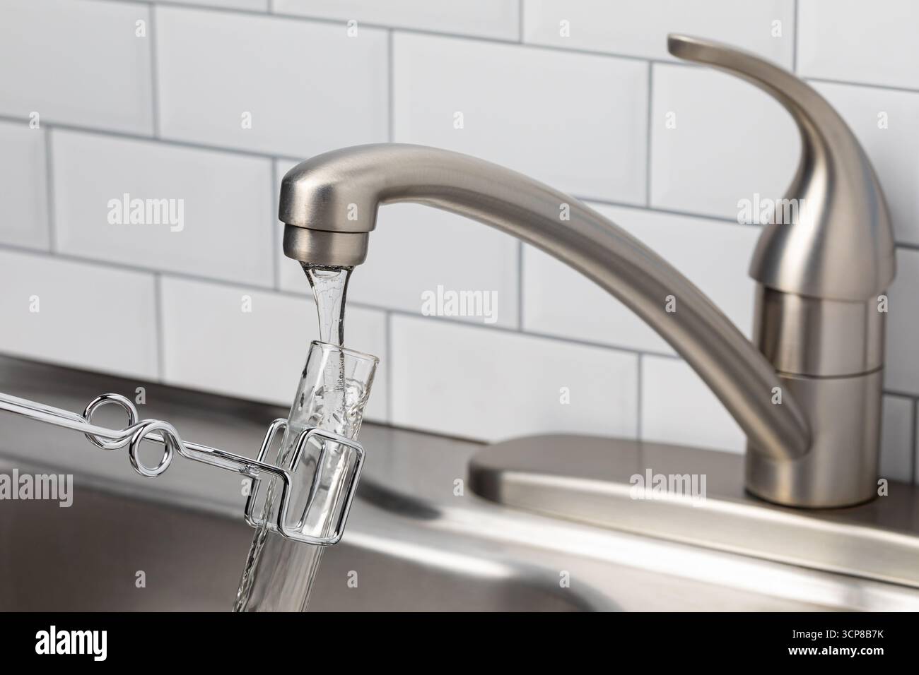 Test dell'acqua di rubinetto dal rubinetto. Concetto di contaminazione dell'acqua potabile, inquinamento da plastica e qualità dell'acqua. Foto Stock