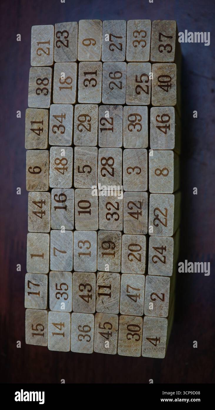 Primo piano di blocchi di legno con numeri incisi disposti in una griglia su una superficie scura. Foto Stock