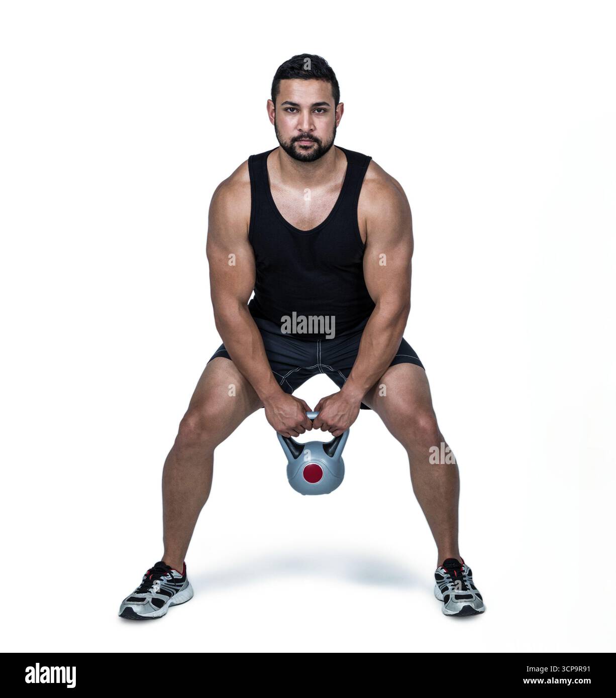 Uomo muscoloso che solleva kettlebell, concentrandosi sull'allenamento di forza e il fitness Foto Stock