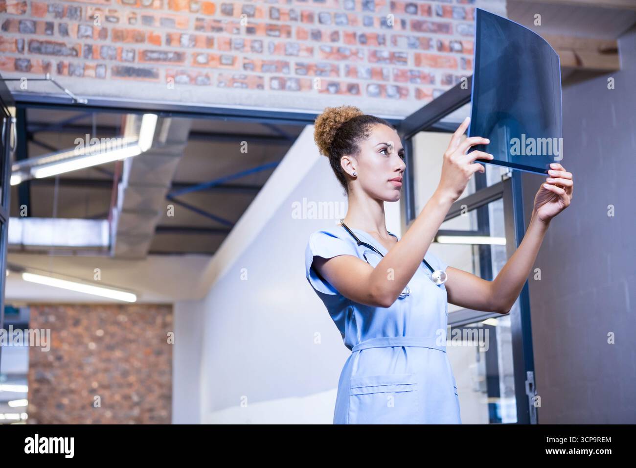 Pellicola per raggi X tenuta contro la luce in corridoio clinico, con pareti in mattoni e condotti Foto Stock
