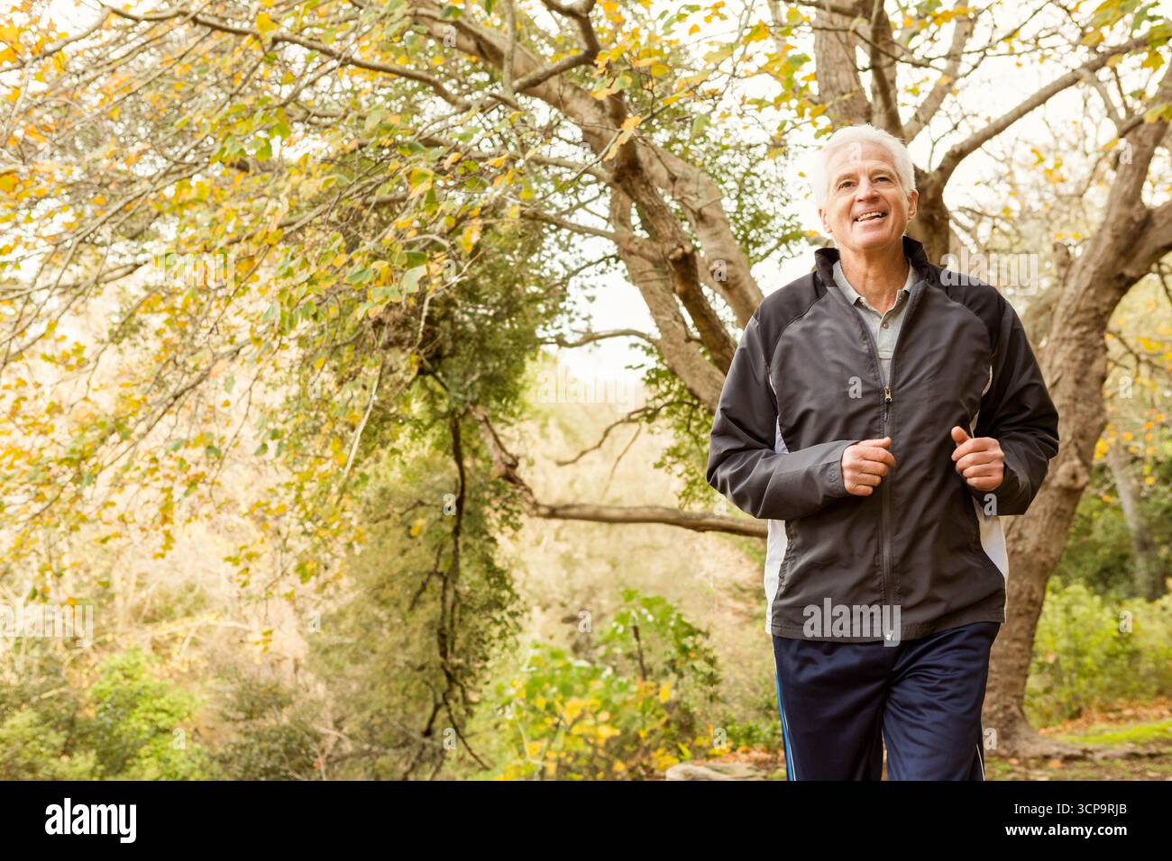 Pista da jogging per uomini senior con giacca da running scura, pantaloni da atletica, spazio per fotocopie Foto Stock