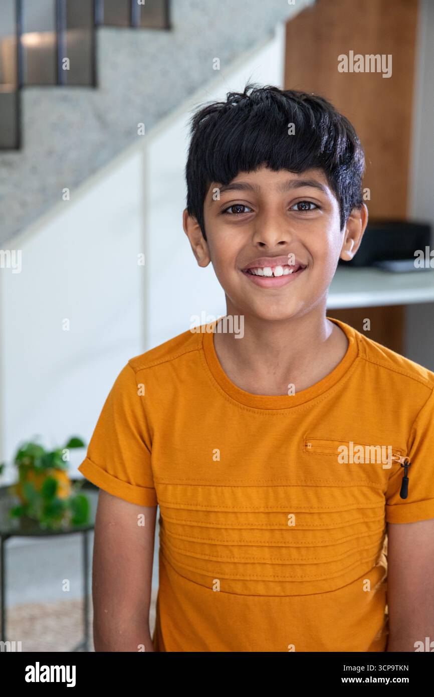 Ragazzo dell'asia meridionale in piedi in un corridoio moderno accanto a pareti a motivi geometrici e ringhiere per scale Foto Stock