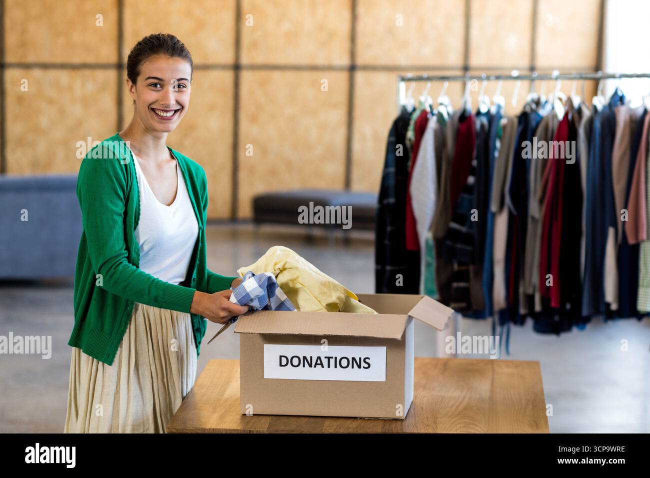 Donna volontaria che ordina gli abiti in una scatola per donazioni nella stanza di smistamento in base al portapacchi, copia dello spazio Foto Stock
