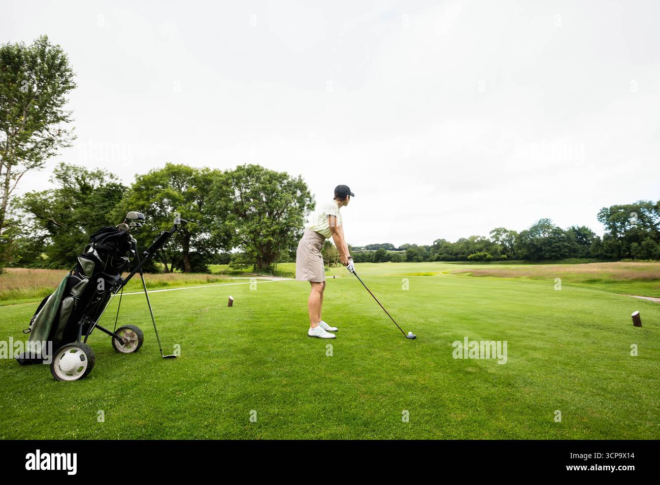 Senior golfista che tiene in mano il conducente mentre si trova sul tee box sopra la palla da golf e si prepara a guidare Foto Stock