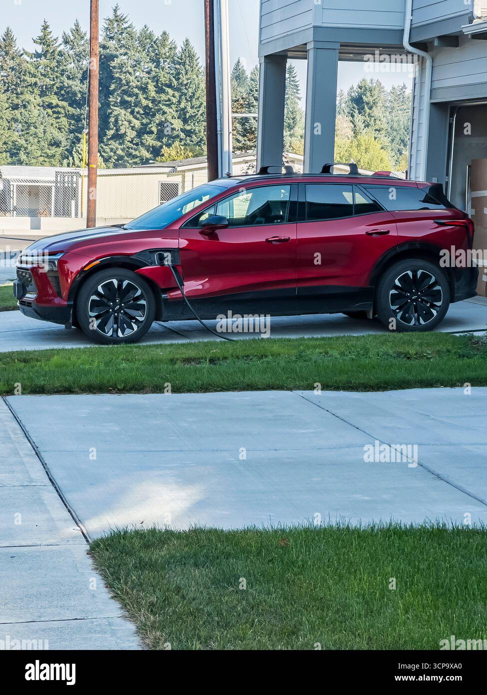 Chevy Blazer RS EV SUV si ricarica in un vialetto di una casa in periferia. - Immagine stock catturata con smartphone