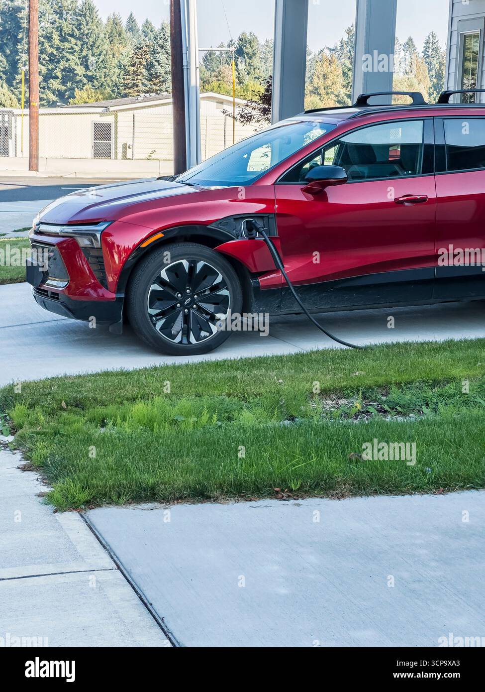 Chevy Blazer RS EV SUV si ricarica in un vialetto di una casa in periferia. - Immagine stock catturata con smartphone