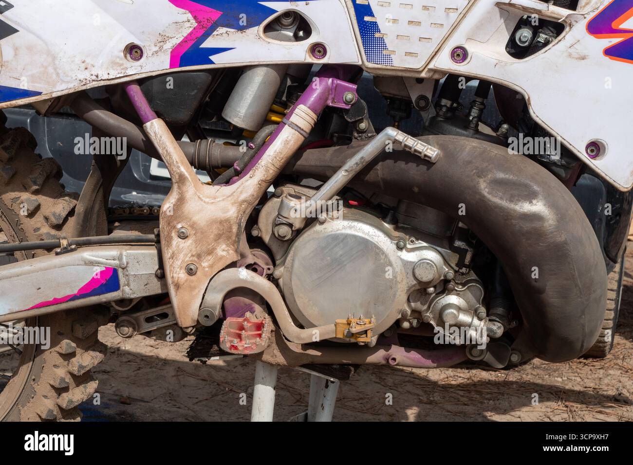 Moto da terra con verniciatura rossa e viola. La bicicletta è parcheggiata in una zona fangosa Foto Stock