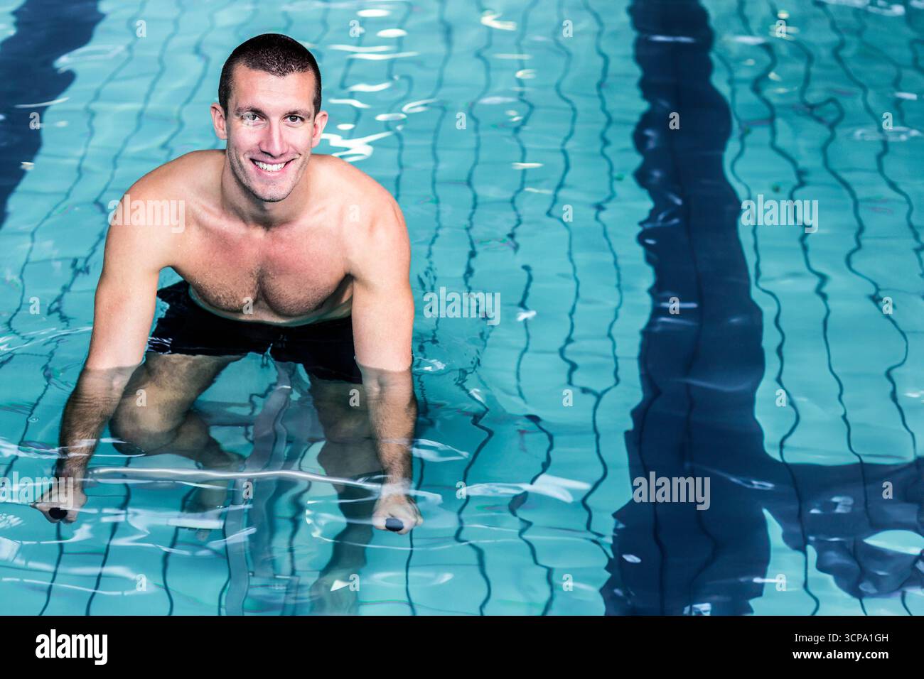 I manubri Aqua riposano immersi sul pavimento della piscina con corsie piastrellate e schemi luminosi ondulati Foto Stock