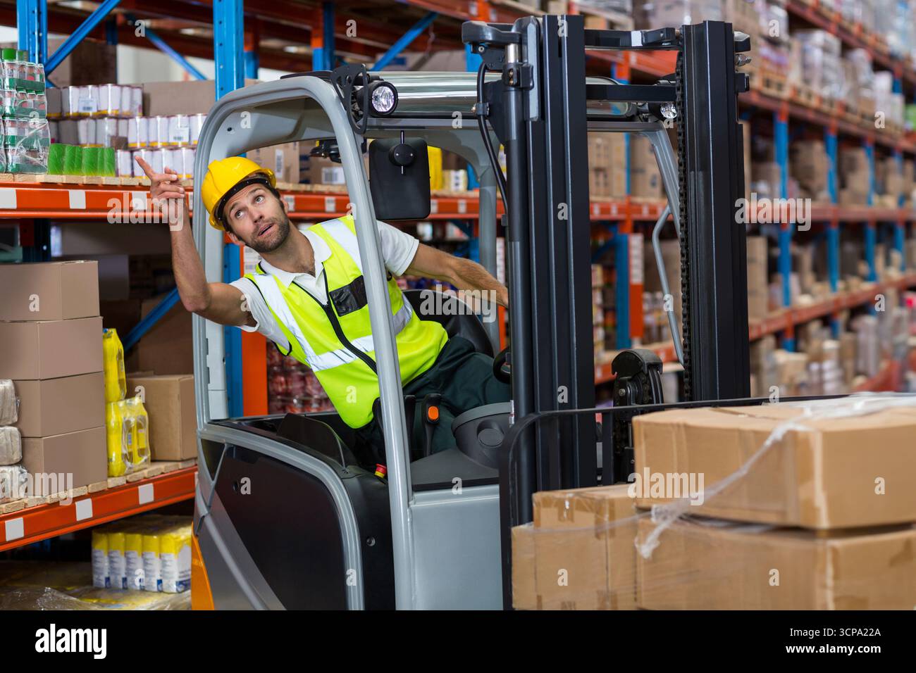 il carrello elevatore solleva pallet avvolti dallo scaffale superiore del magazzino, con scaffali blu e arancioni Foto Stock
