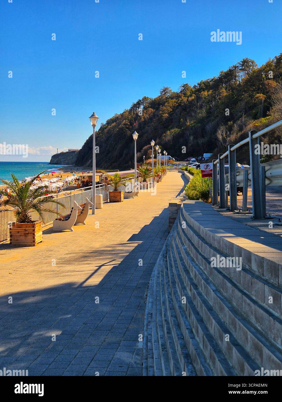 Una passeggiata soleggiata con vista sul mare. Vista panoramica del sentiero pedonale lungo la riva del mare. - Immagine stock catturata con smartphone