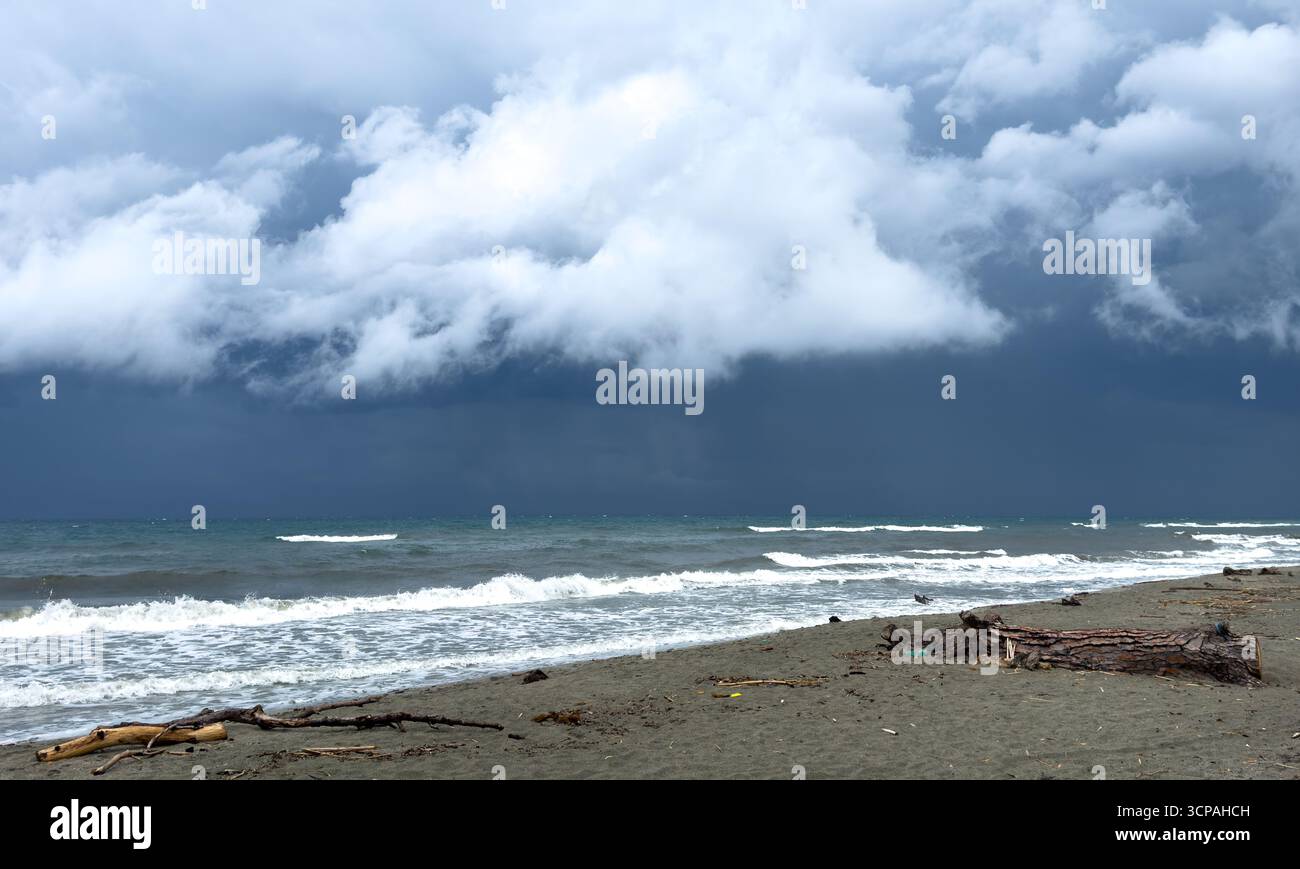 tempesta con forti nuvole di pioggia e onde che si infrangono sulla spiaggia Foto Stock