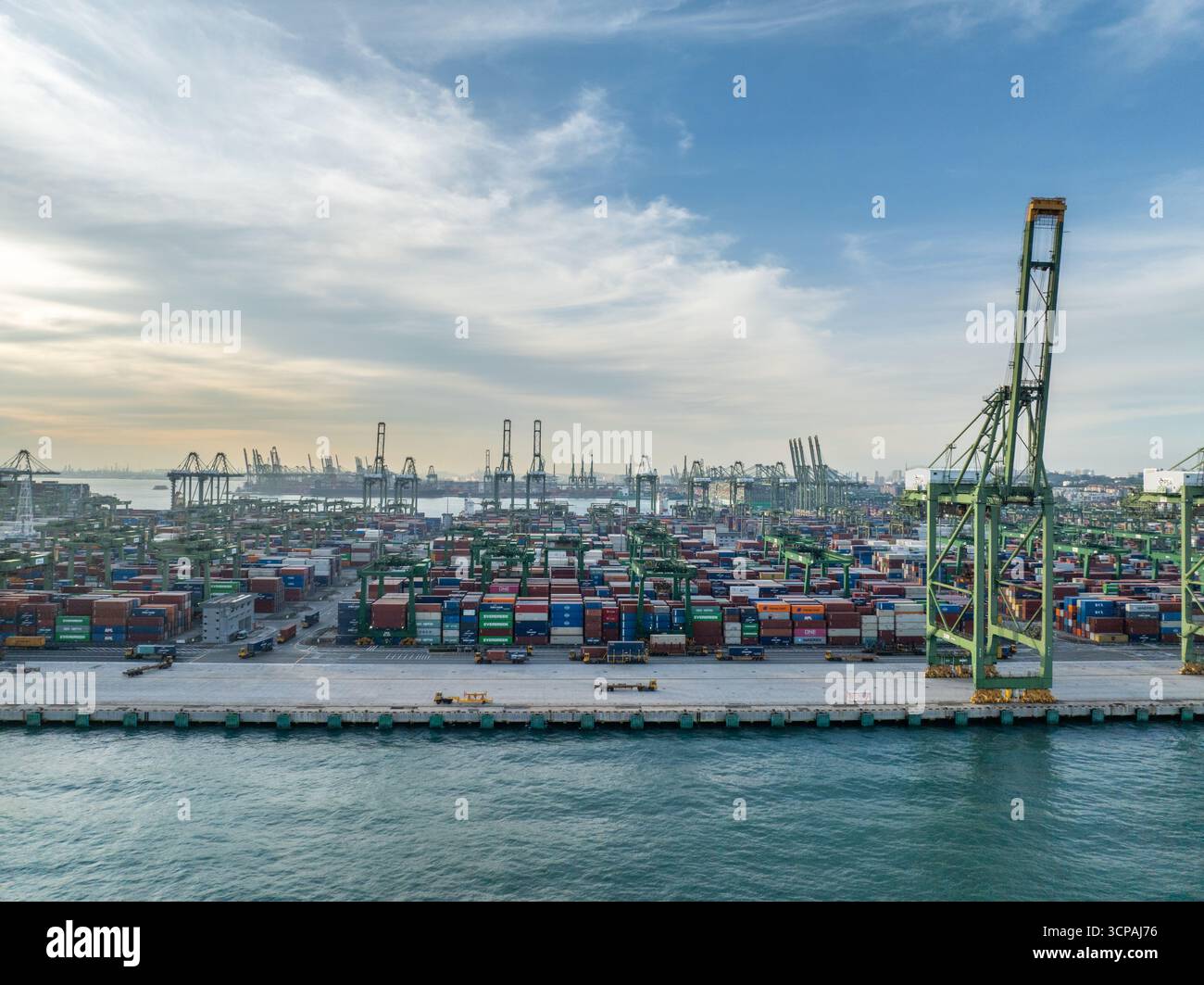 Singapore, Singapore - 06 dicembre 2024: Vista aerea del terminal Pasir Panjang, un vasto arazzo di contenitori impilati immersi nella luce soffusa sullo sfondo di torreggianti gru. Foto Stock