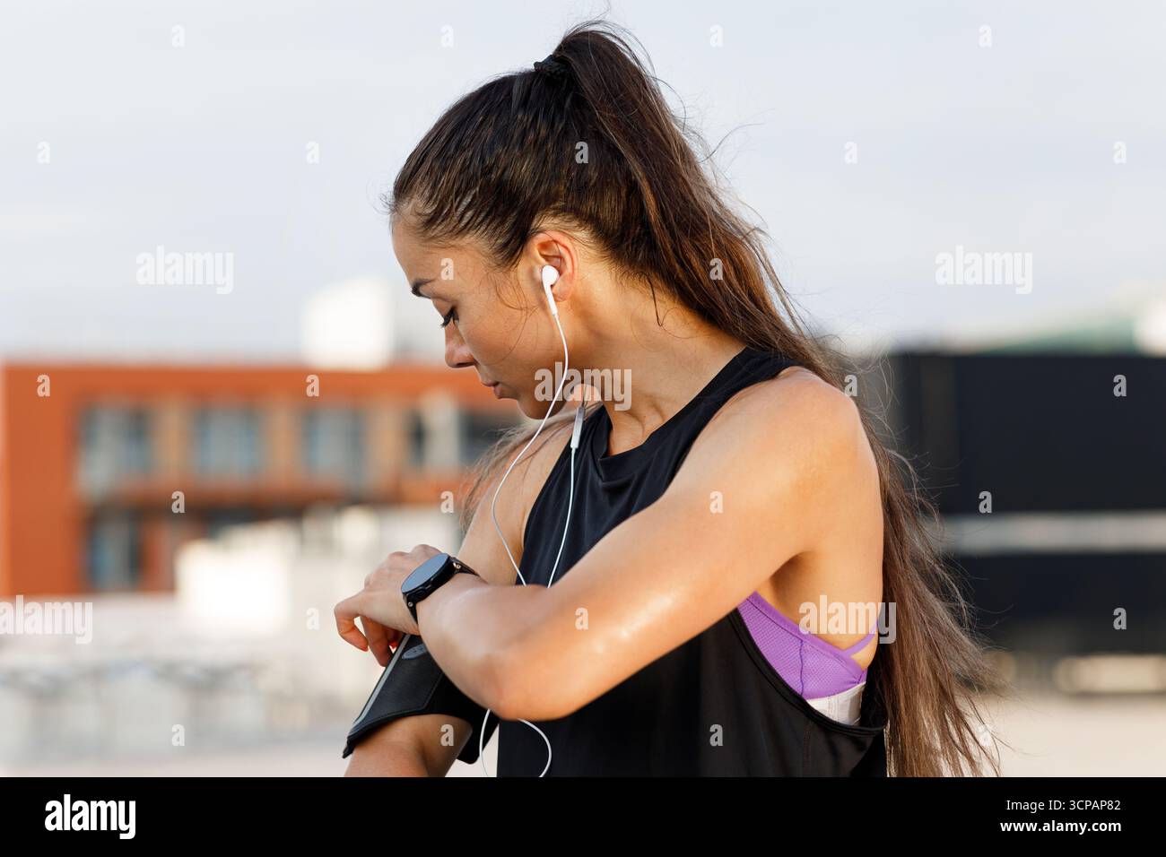 Donna che controlla il suo telefono sulla banda sulla mano durante un allenamento Foto Stock