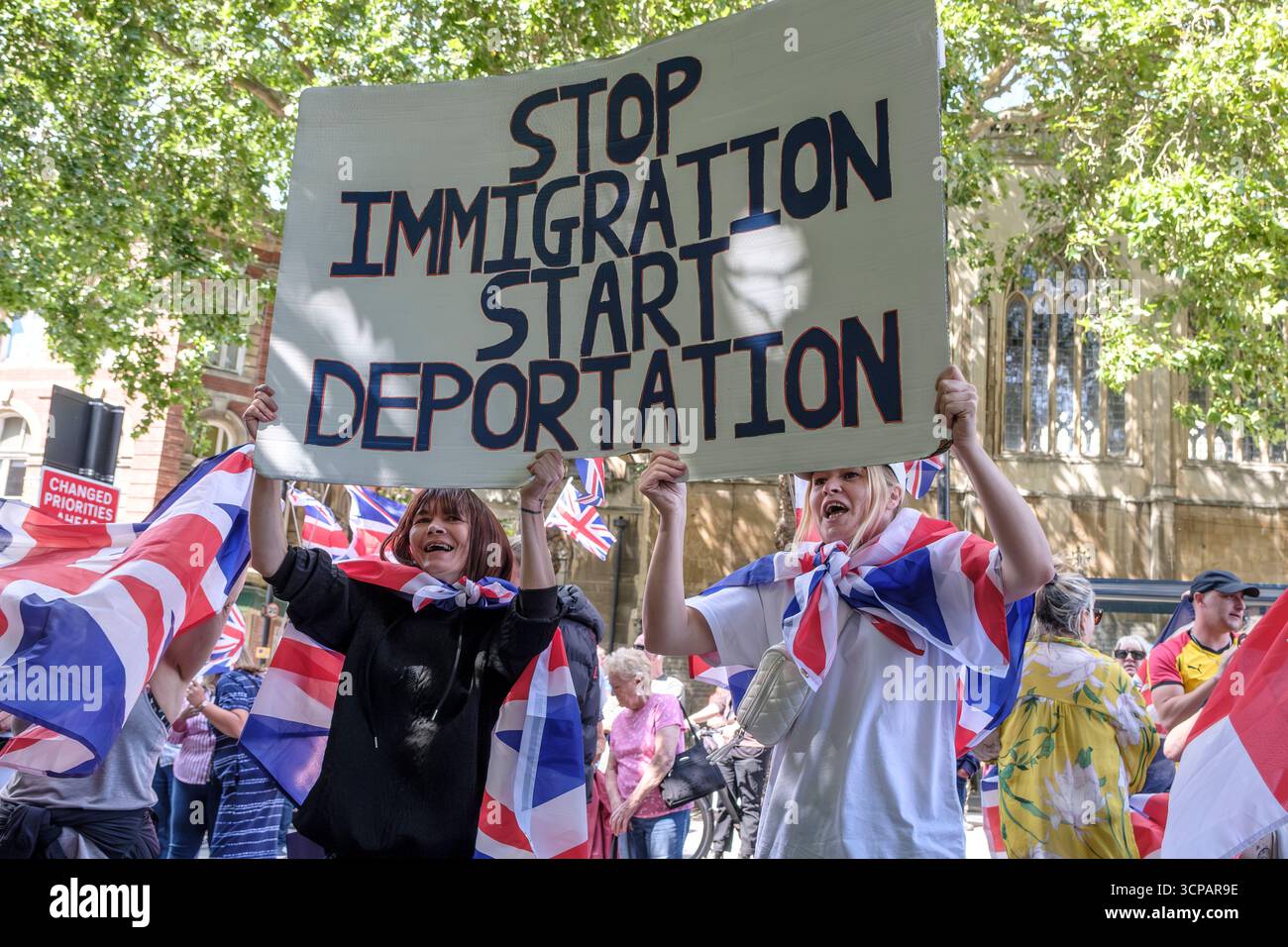 I manifestanti antifascisti e di estrema destra contro l'immigrazione di Bristol si sono urlati l'un l'altro tutto il pomeriggio a Castle Park Bristol, la polizia ha cercato di tenerli separati. Cartello Interrompi immigrazione/Avvia deportazione Foto Stock