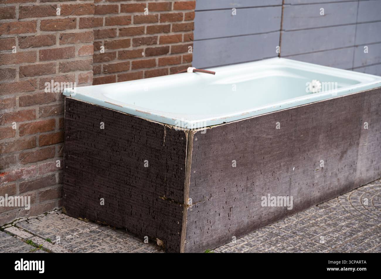 Una vasca da bagno tradizionale è posizionata di fronte a una parete in mattoni, creando un contrasto distintivo nei materiali e negli elementi di design Foto Stock