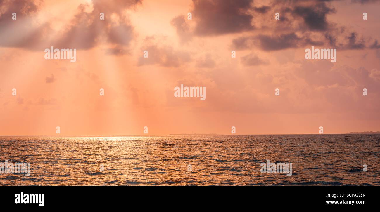 Il fantastico tramonto dorato sul mare calmo con cielo spettacolare, nuvole morbide e raggi luminosi del sole sognano un tranquillo sfondo naturale e una tranquilla vista sul mare Foto Stock