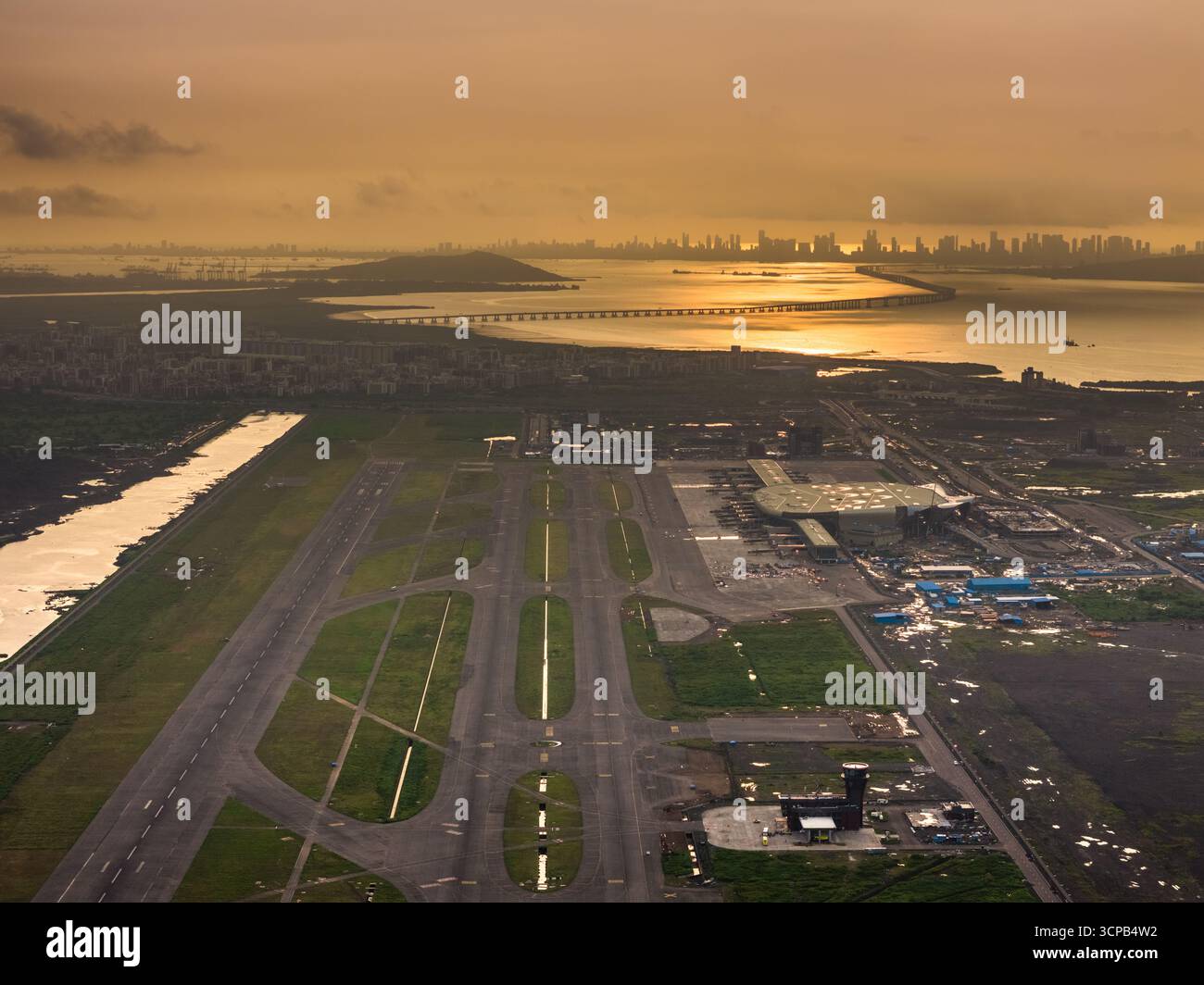Vista aerea dei lavori in corso di costruzione dell'aeroporto internazionale navi Mumbai (NMIA), della pista e dell'edificio del terminal immersi nel caldo bagliore del tramonto, navi Mumbai, Maharashtra, India. Foto Stock