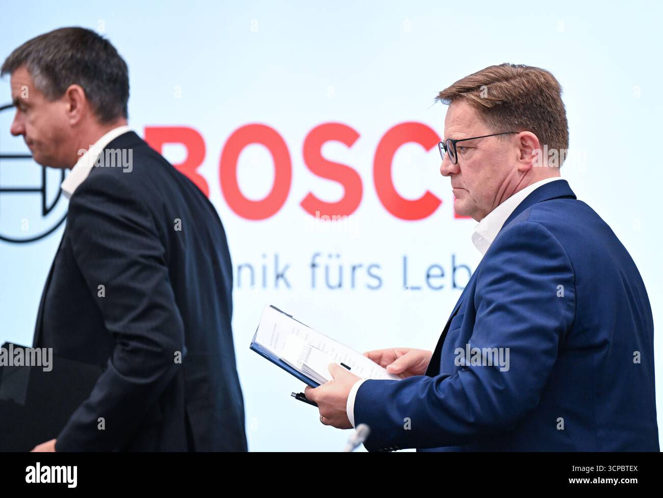 Gerlingen, Germania. 25 settembre 2025. Stefan Grosch (r), membro del Consiglio di amministrazione e direttore del lavoro della Robert Bosch GmbH, lascia la sala conferenze dopo una conferenza stampa sui tagli al lavoro. Sulla sinistra c'è Thomas Pauer, presidente della divisione Power Solutions di Robert Bosch GmbH. Crediti: Bernd Weißbrod/dpa/Alamy Live News Foto Stock