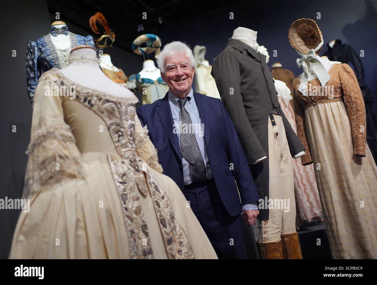Il costumista vincitore di Oscar e BAFTA John Bright posa i prossimi costumi in mostra, tra cui (da sinistra a destra) un abito da sposa degli anni '1770 dal film Mary Shelley's Frankenstein (1994), indossato da Helena Bonham Carter; e un vestito e un vestito anni '1810 per la serie tv della BBC Pride and Prejuence (1995), indossato da Colin Firth e Jennifer Ehle, in anteprima di Costume Couture: sessant'anni della mostra Cosprop, al Fashion & Textile Museum nel centro di Londra, che va dal 26 settembre all'8 marzo. Data foto: Giovedì 25 settembre 2025. Foto Stock