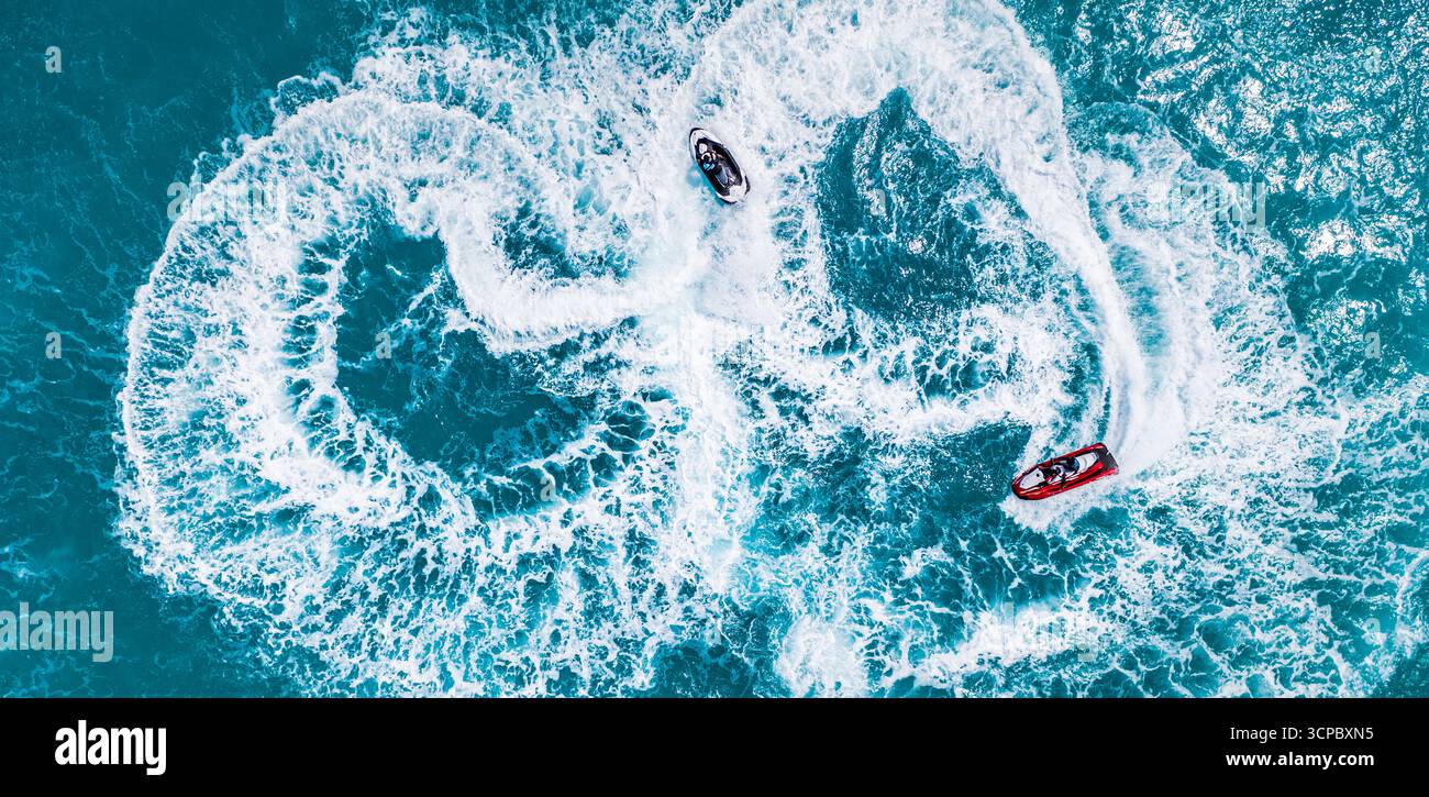 Fantastico sport acquatici all'aperto sullo sfondo due motociclisti che si divertono con la laguna oceanica in estate, avventura e velocità. Le onde si tuffano nella baia Foto Stock