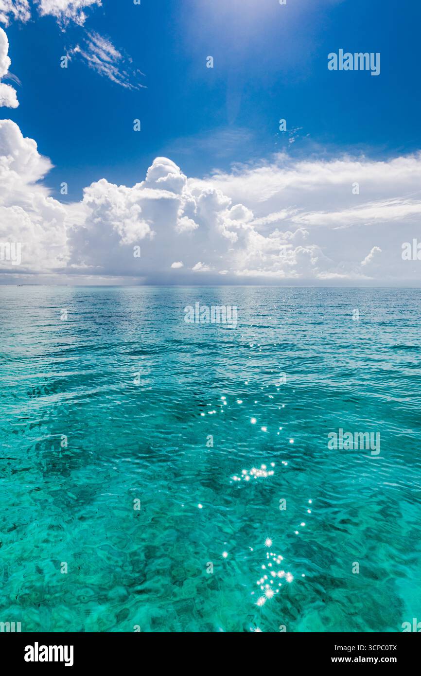 Splendida vista sull'oceano tropicale con un orizzonte rilassante. Calmo mare, cielo tranquillo e nuvole morbide. Sfondo naturale perfetto. Barriera corallina poco illuminata dal sole Foto Stock