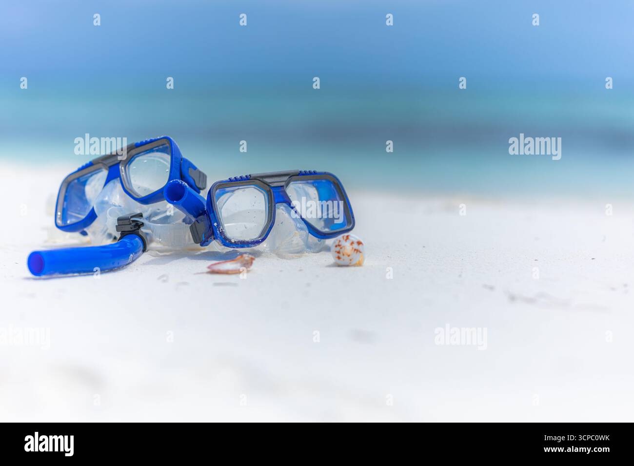 Primo piano dell'attrezzatura da snorkeling sulla spiaggia estiva. Maschera, boccaglio attività ricreative all'aperto. Mare, cielo e orizzonte sfocati. Natura morta astratta in sabbia soleggiata Foto Stock